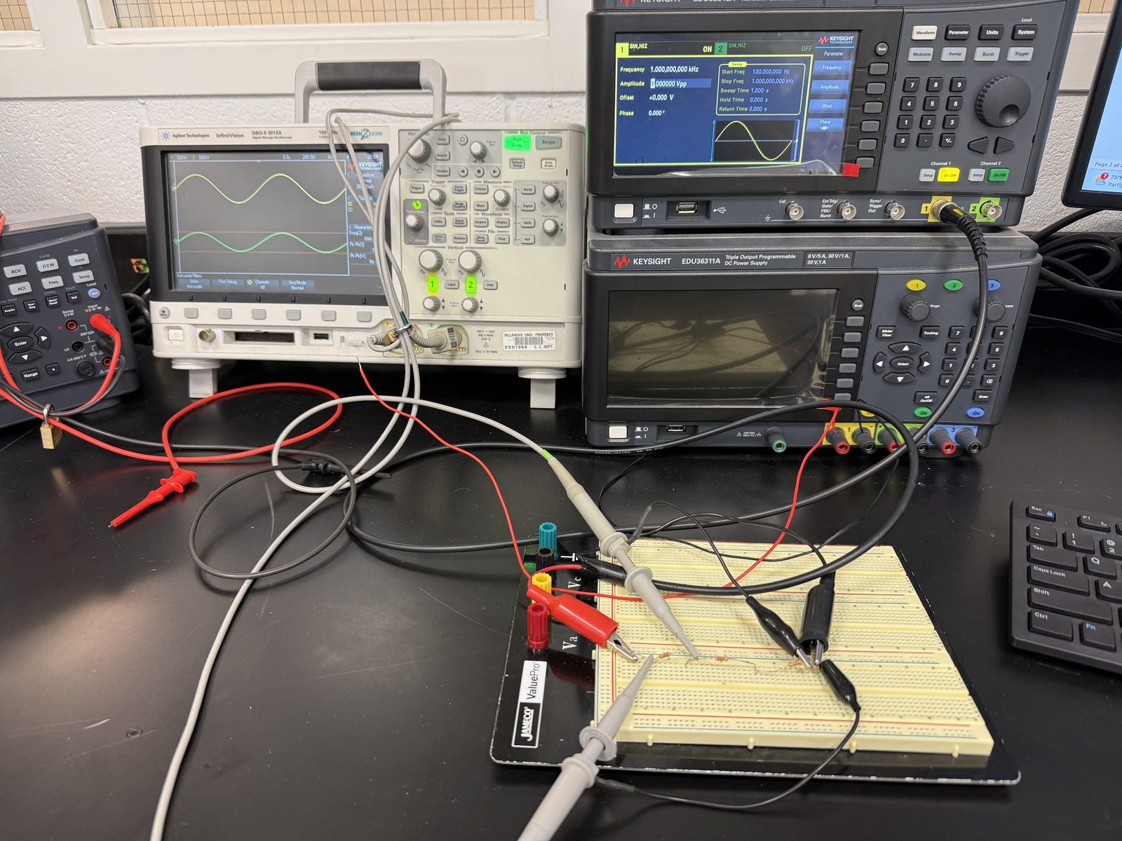 Analog electronics lab bench with oscilloscope, function generator, power supply, and a breadboard circuit