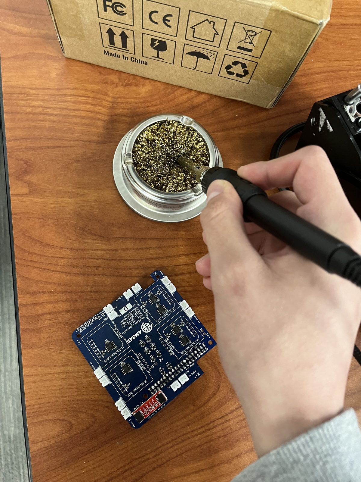 Soldering a CubeSat solar power board on a lab bench