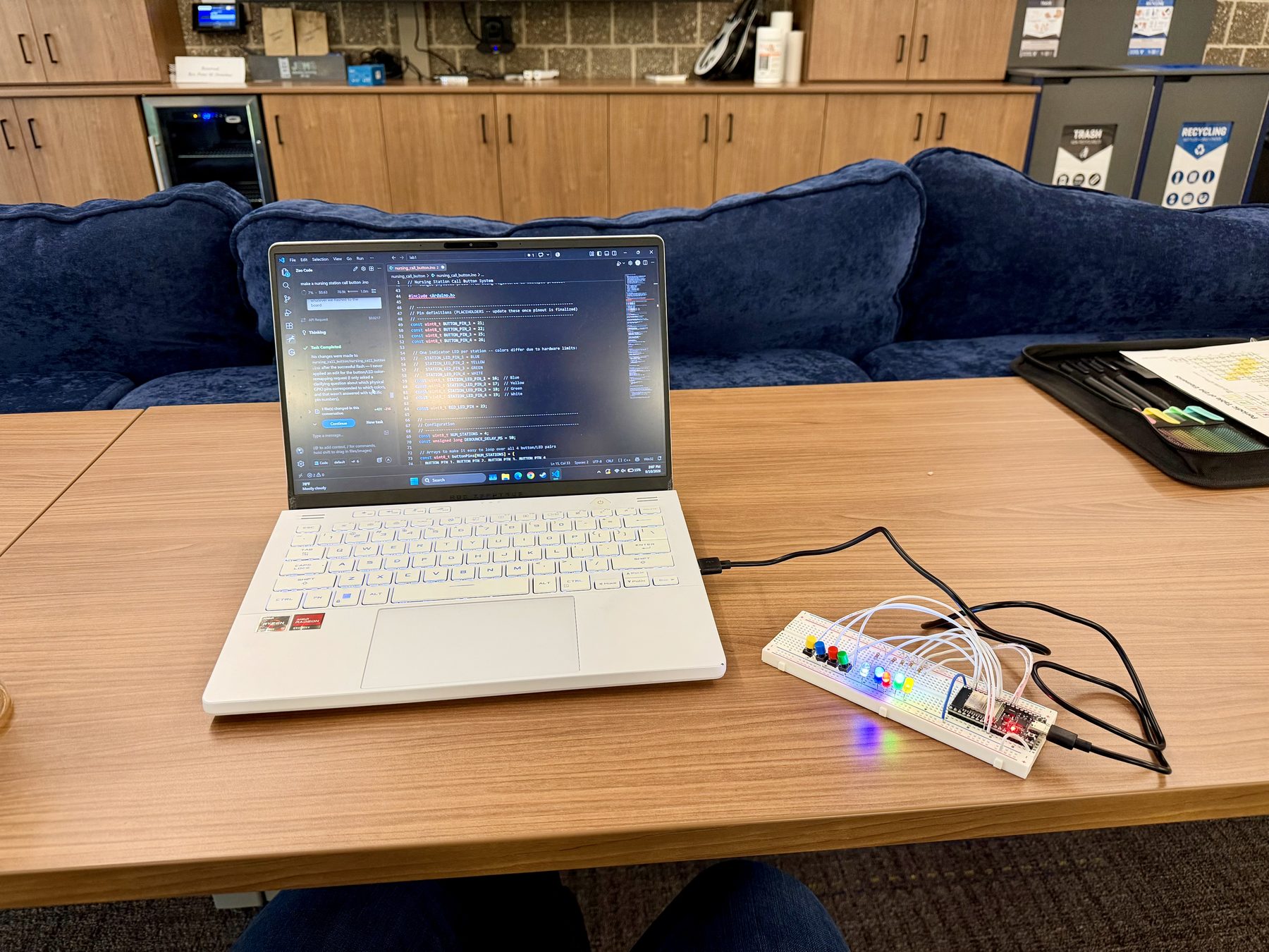 Bench setup for the nursing call button lab, with a laptop beside a breadboard, ESP32, colored buttons, and lit LEDs