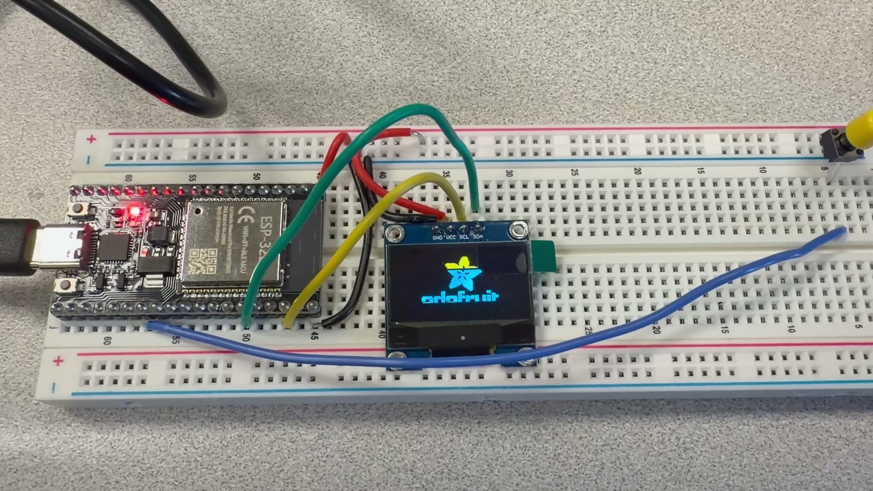 ESP32 wired to an SSD1306 OLED showing the Adafruit logo
