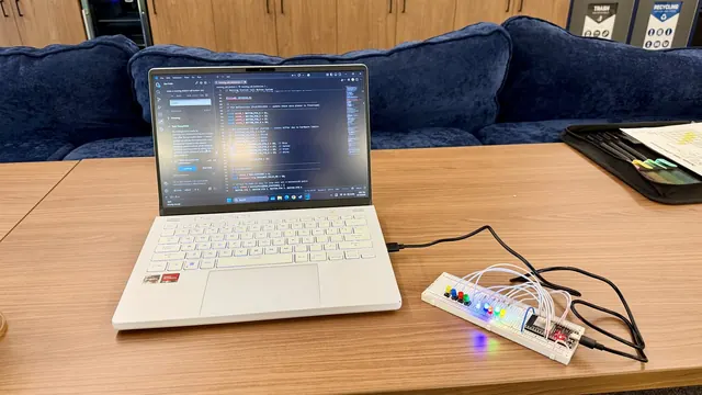 Bench setup for the nursing call button lab, with a laptop beside a breadboard, ESP32, colored buttons, and lit LEDs